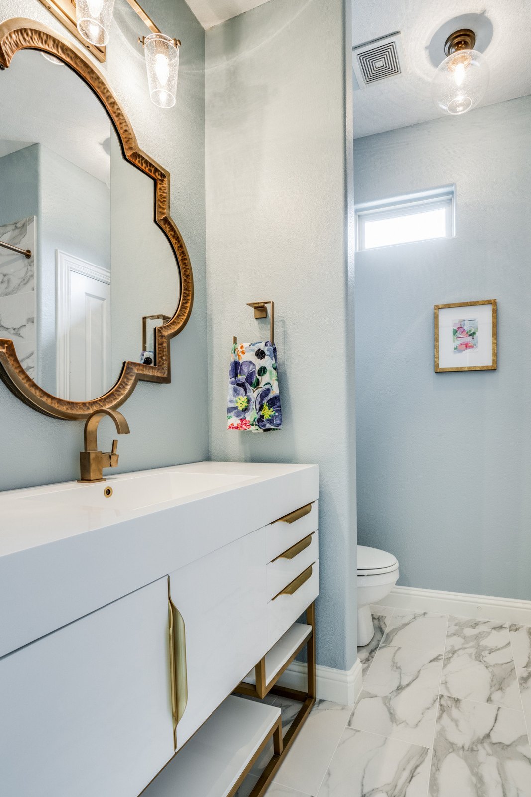 Modern master bathroom with a floating stone vanity and a gold-framed mirror, built by Chateau Concepts in Dallas