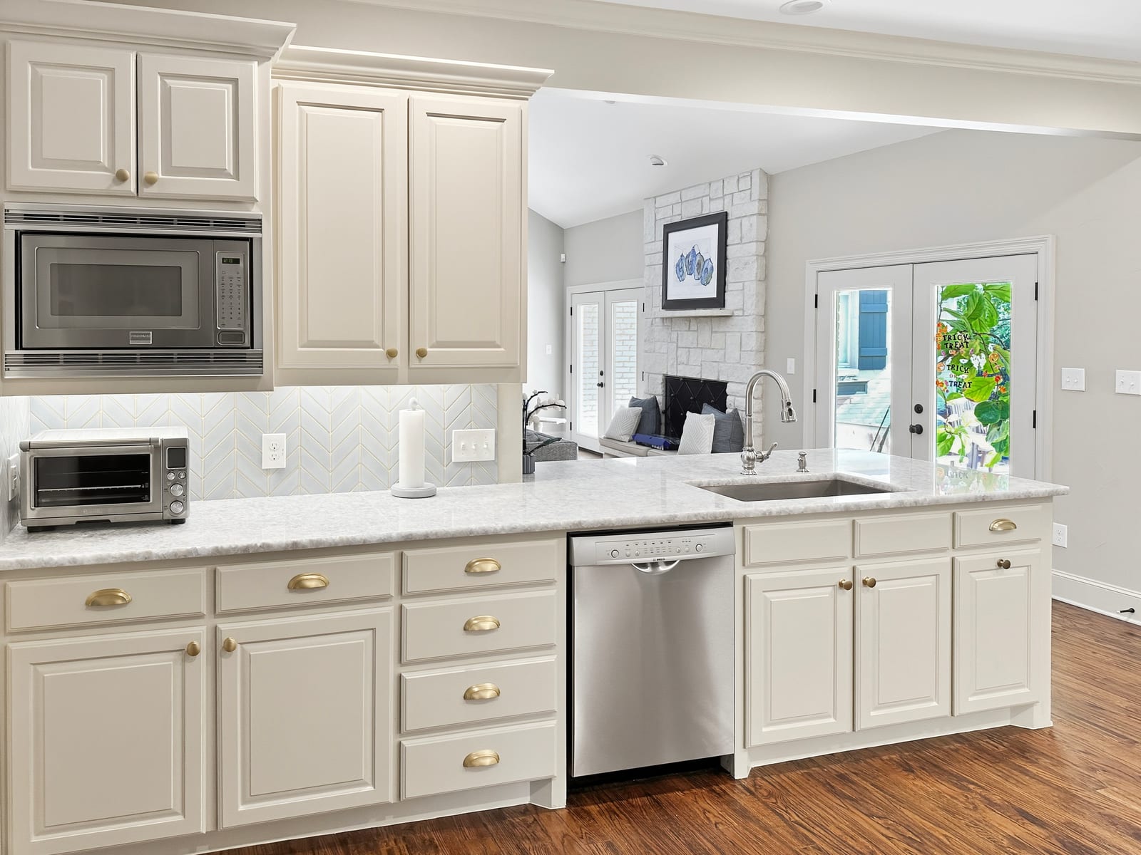 Kitchen with glazed cream cabinetry, light stone counters and hardwood floors